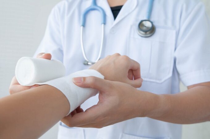 Doctor bandaging the wrist. Concept of first aids and treatment in wrist injuries.